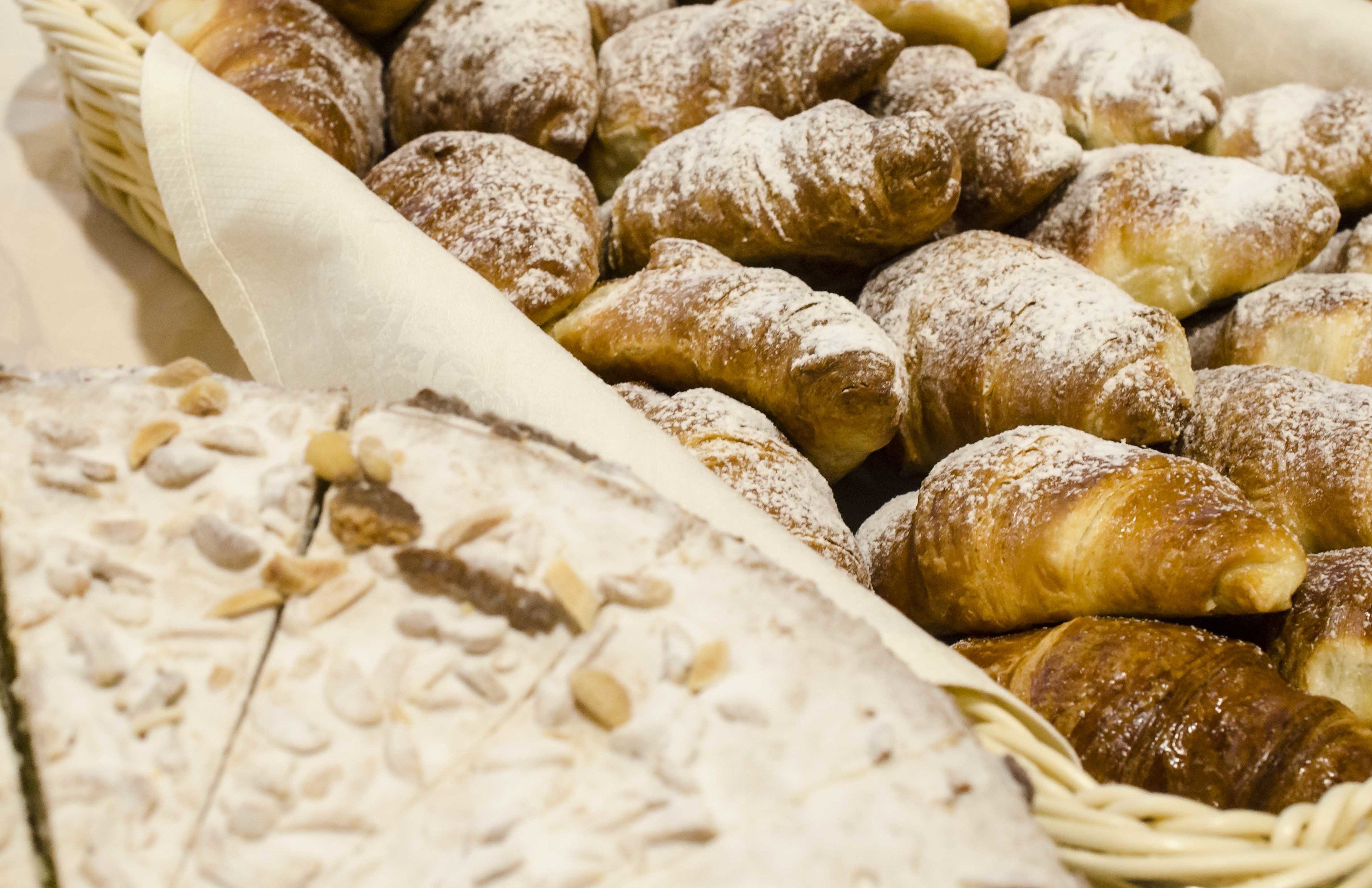 Ein Korb mit verschiedenen Backwaren, darunter Croissants und Brot mit Saaten.