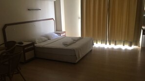 A hotel room with a bed, a nightstand, a chair, and a window with curtains. - Zeytin Apart Otel (Cesme)