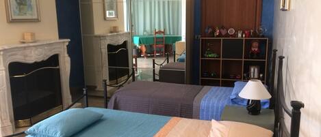 Una habitación con cama, chimenea, espejo, estantería y lámpara.