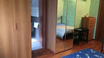 Una camera da letto con un'armadietto in legno, un letto con copripiumino a fiori blu, una scrivania e un comò.