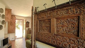 Een kamer met een houten gebeeldhouwd hoofdeinde, een televisie op een houten standaard en een groene bank.