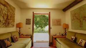 Een gezellige kamer met twee banken gericht op een groot raam, een houten balk in het plafond en kunstwerken aan de wanden.