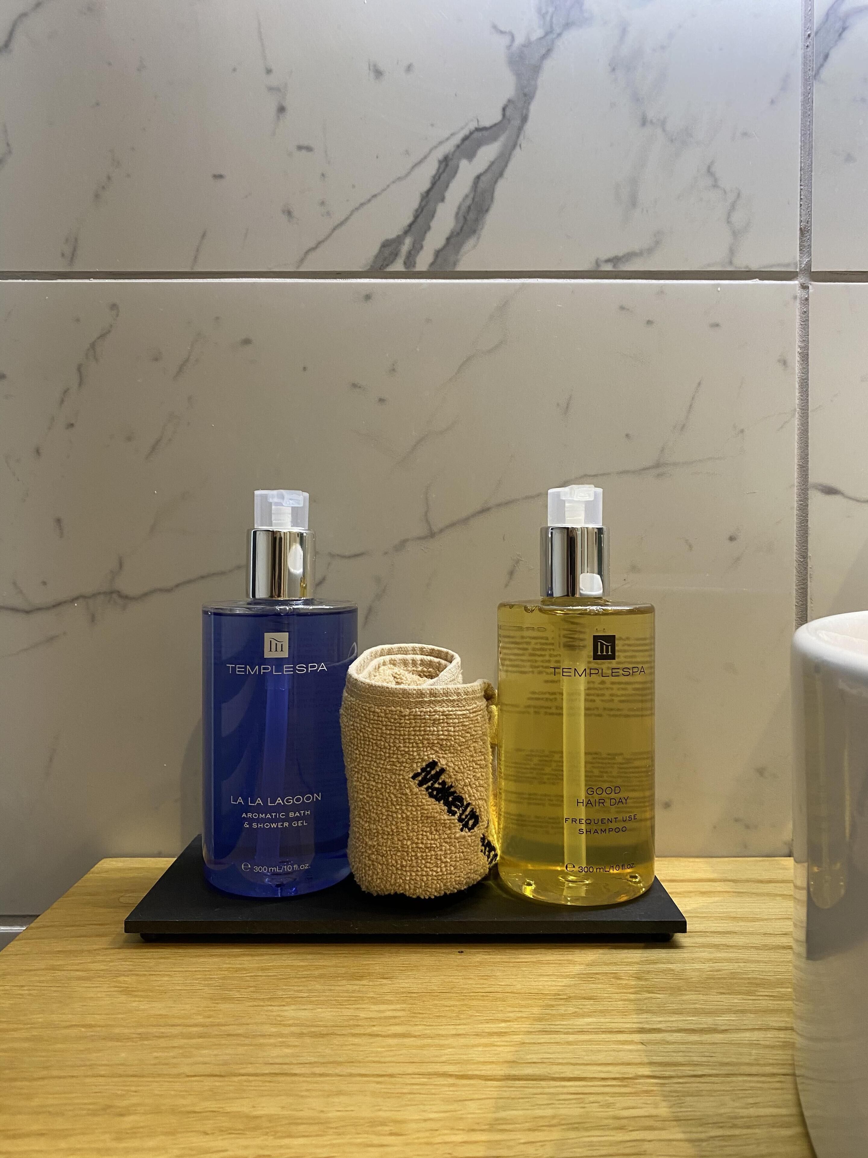 Uma prateleira no banheiro com dois produtos TempleSpa e uma toalha.
