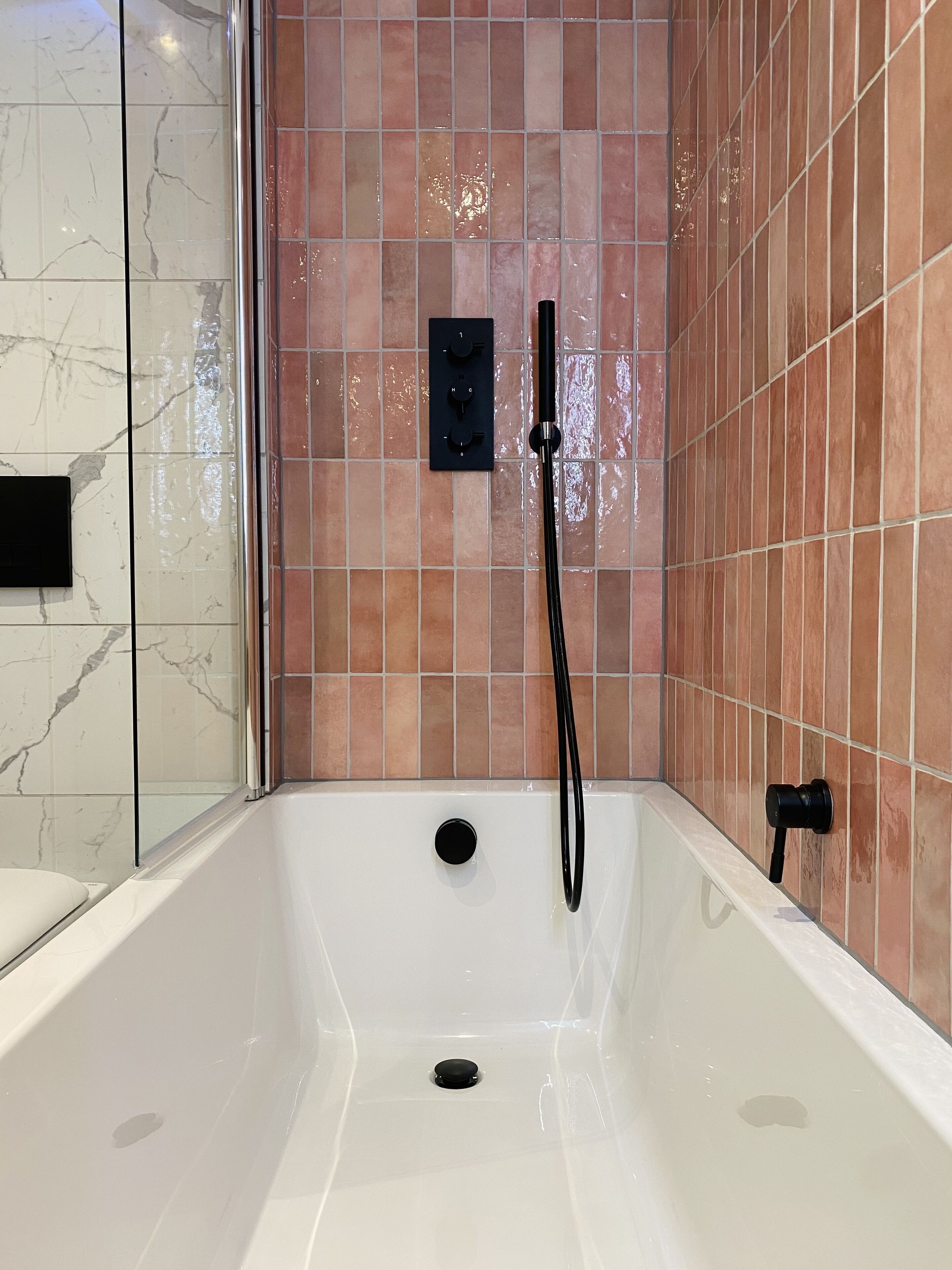 A modern bathroom with a bathtub, a shower head, and a control panel.