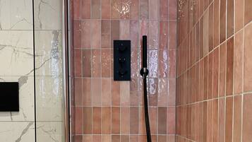A modern bathroom with a bathtub, a shower head, and a control panel.