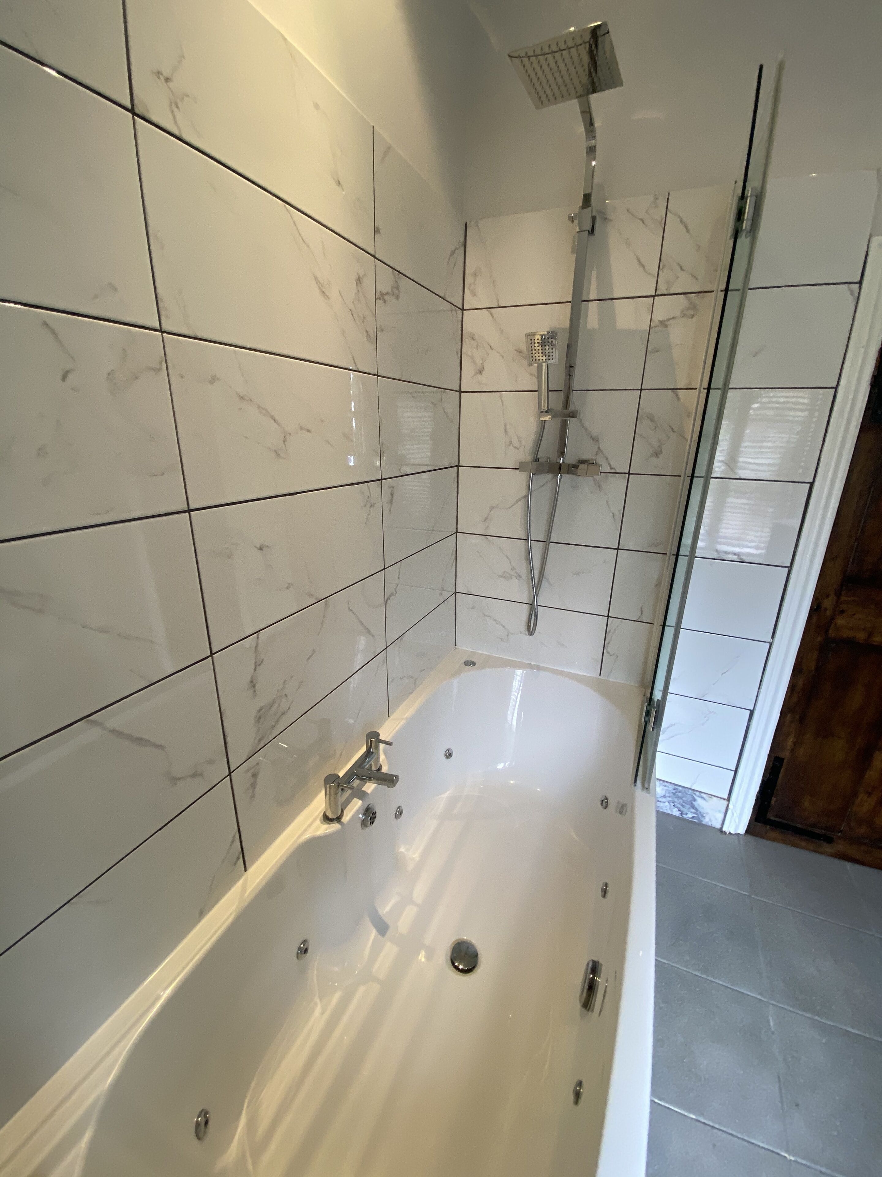 A modern bathroom with a freestanding bathtub, a showerhead, and tiled walls.