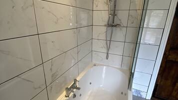 A modern bathroom with a freestanding bathtub, a showerhead, and tiled walls.