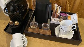 Una bandeja con cafetera, dos tazas, dos pequeños frascos, una bandeja de sobres de café y una tetera.