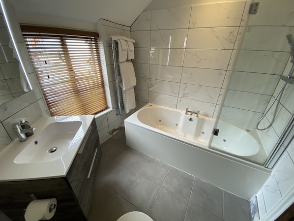 A modern bathroom with a bathtub, a shower, and a vanity with a sink.