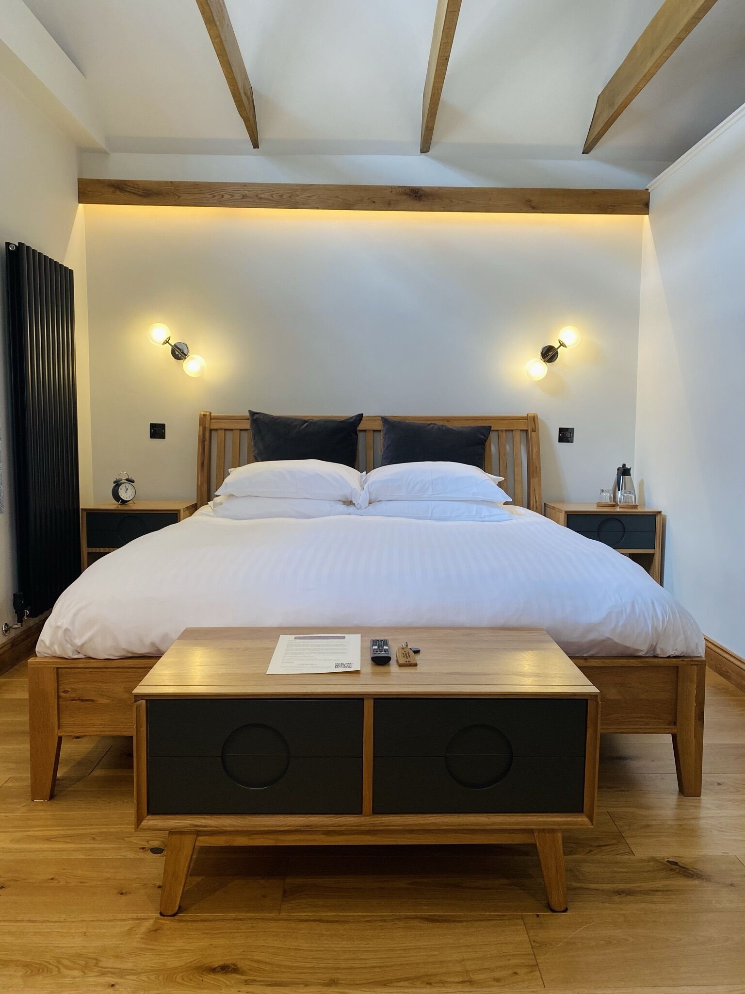 Een slaapkamer met een groot bed, een houten hoofdbord, nachtkastjes en een nachtkastje met een lamp.