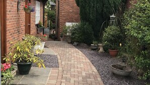 Un camino de ladrillo que lleva a una casa con jardín.