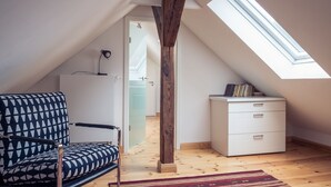 A loft bedroom with a sloped ceiling, a wooden beam, a desk, a chair, and a skylight. - Hermannsmühle (Treuenbrietzen)