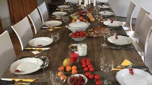 A long dining table set for a meal with white plates, cutlery, and glasses, surrounded by white chairs. - Hermannsmühle (Treuenbrietzen)
