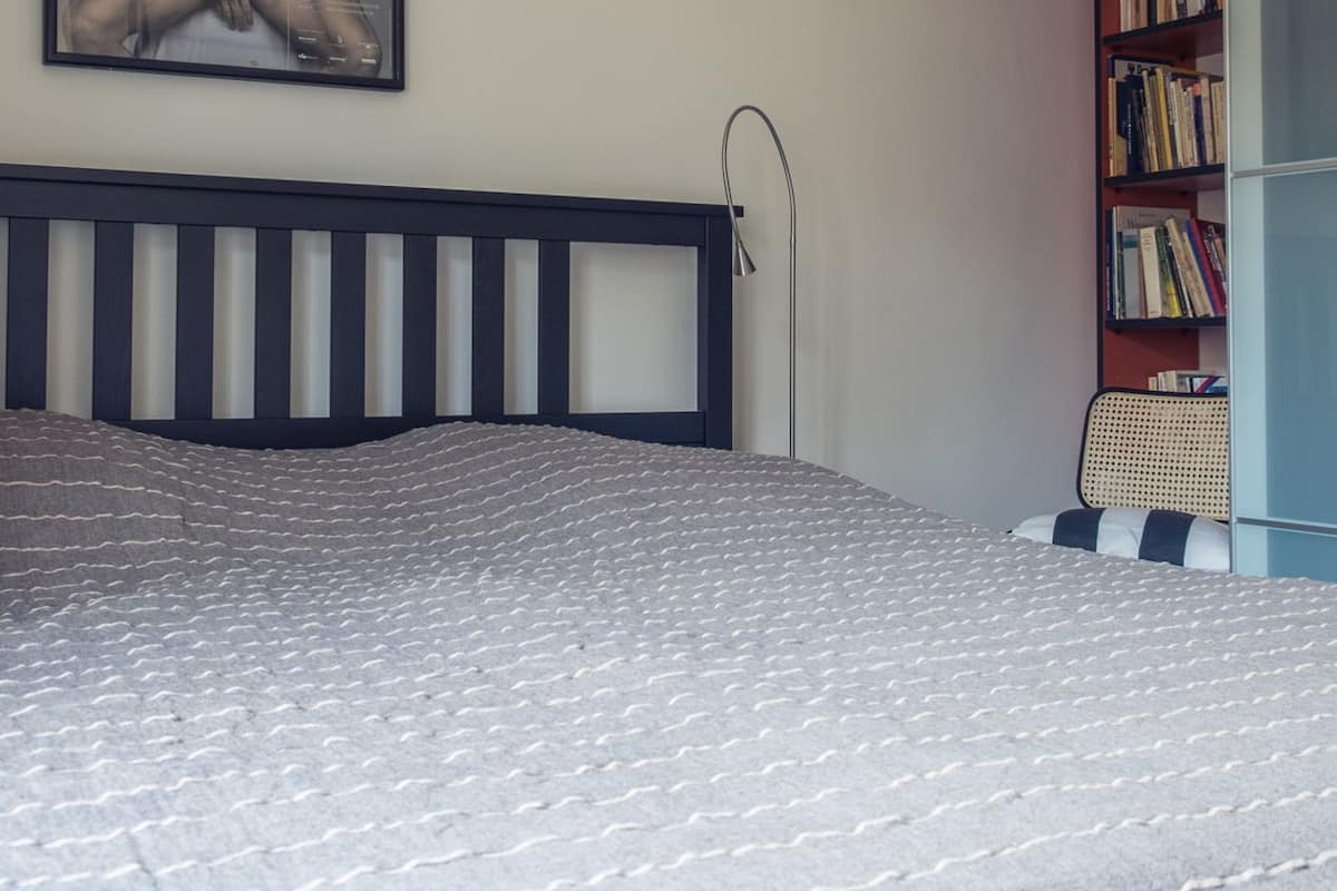 A bedroom with a bed, a bookshelf, and a poster on the wall.