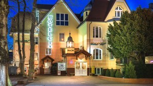 Een hotel in traditionele Europese stijl, met een opvallend naambord, een goed verlichte ingang en een hekwerk oprit.