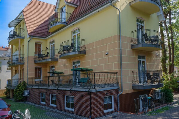 Un edificio de varios pisos con balcones, mobiliario exterior y fachada de ladrillo.
