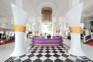 A reception area with a checkered floor, a central counter, and two large pillars with gold accents.