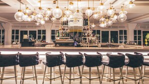 A bar area with multiple hanging light fixtures, a bar counter, and several bar stools. - Dash Resort Langkawi (Langkawi)