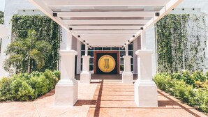 A hotel entrance with a covered walkway, columns, and a large door with a circular emblem. - Dash Resort Langkawi (Langkawi)