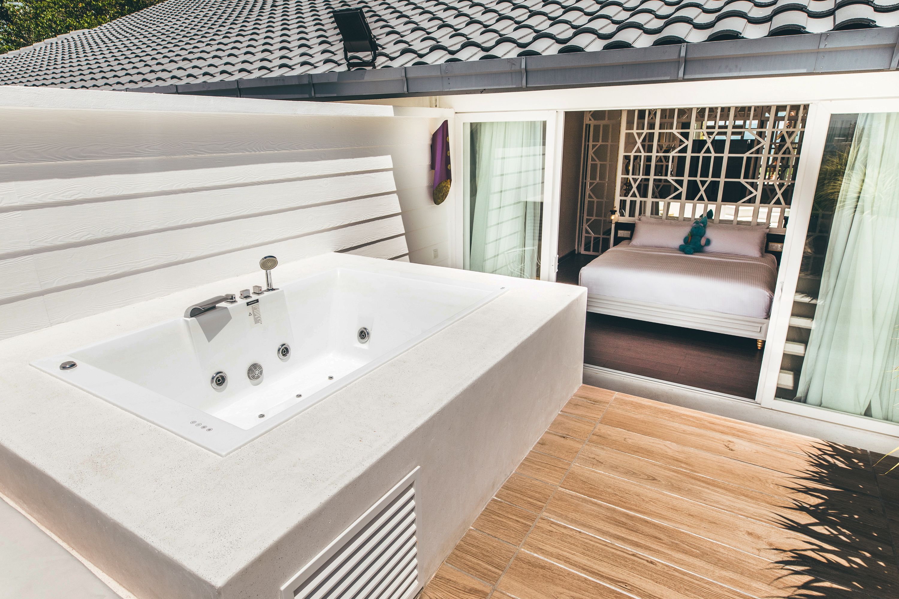 Ein modernes Badezimmer mit einer großen Badewanne, Holzboden und Blick auf den Balkon.