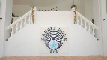 A staircase leading to a spa with a sign reading "Rabbit Hole Spa".