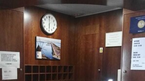 Un comptoir d’accueil avec une horloge, un tableau encadré et un panneau indiquant les heures d’arrivée et de départ.