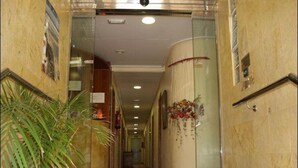 Un couloir d’hôtel avec un pot de fleurs, un extincteur et une caméra de surveillance.