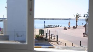 Une vue d’une promenade en bord de mer, avec un ciel dégagé, une mer calme et une allée piétonne.