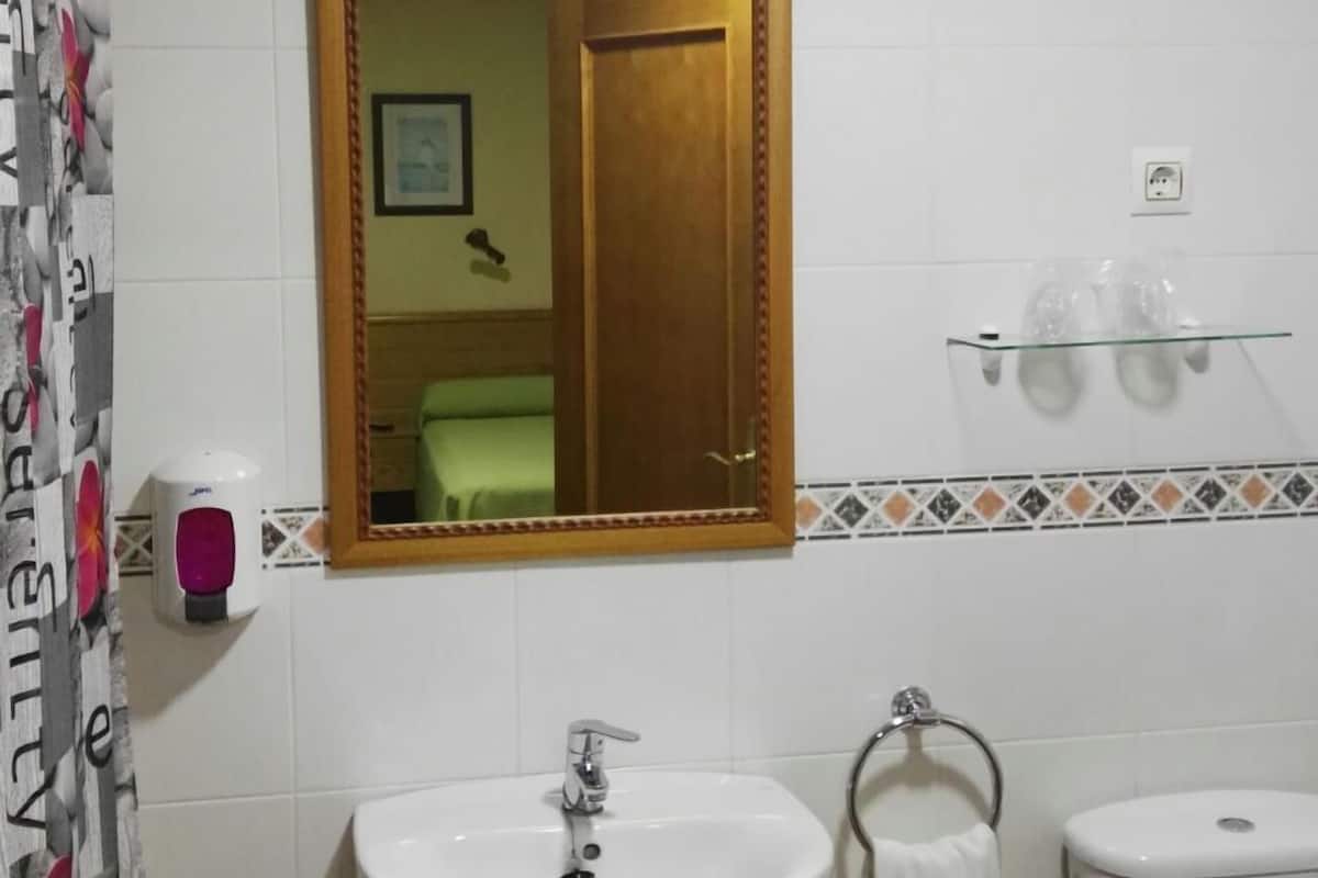 A bathroom with a white sink, a mirror, a toilet, and a shower curtain.