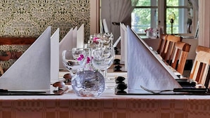 Una mesa de comedor dispuesta con cristalería transparente, un florero de cristal y cubiertos ordenados.