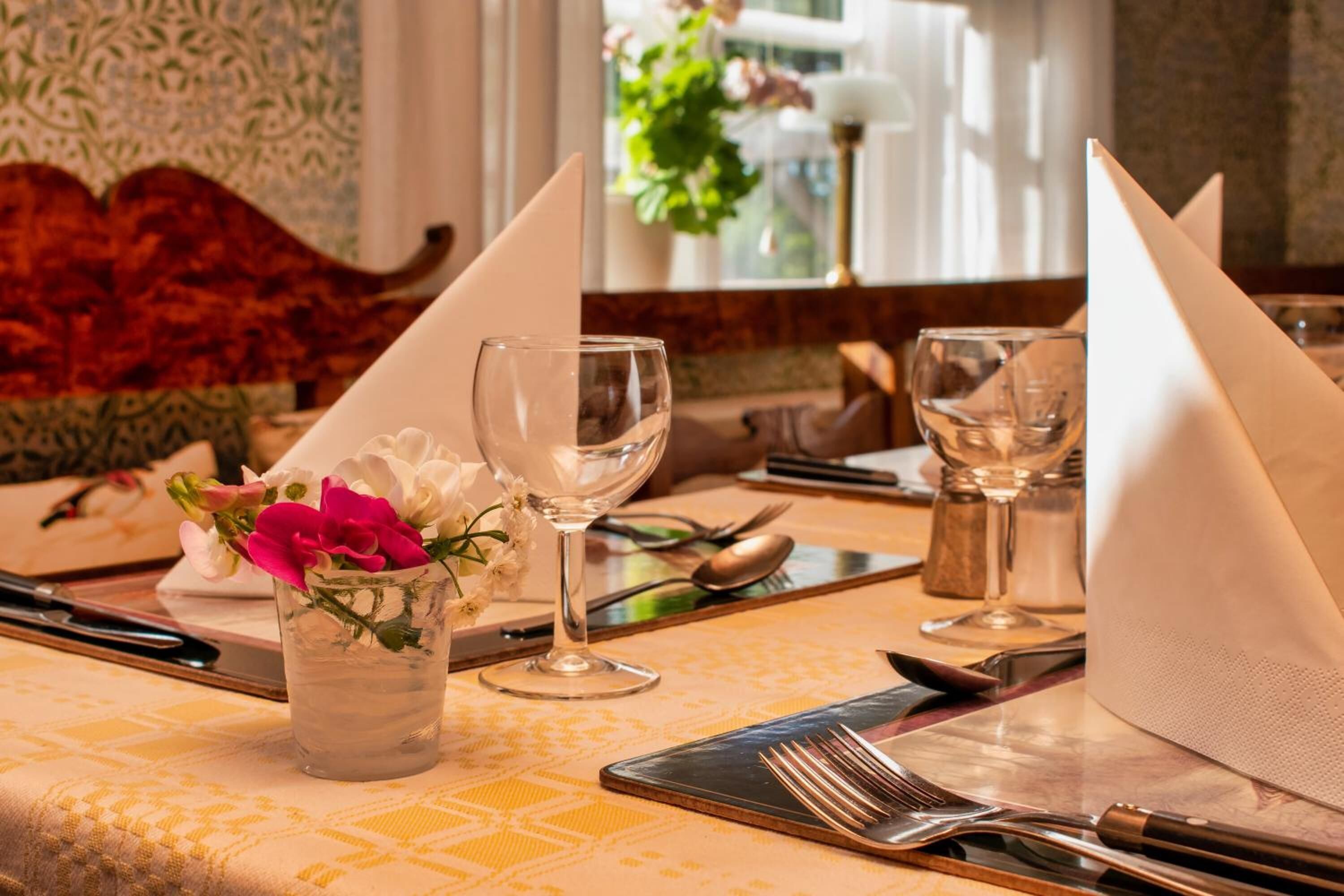A dining table set with a glass of water, a glass of wine, and a folded napkin.