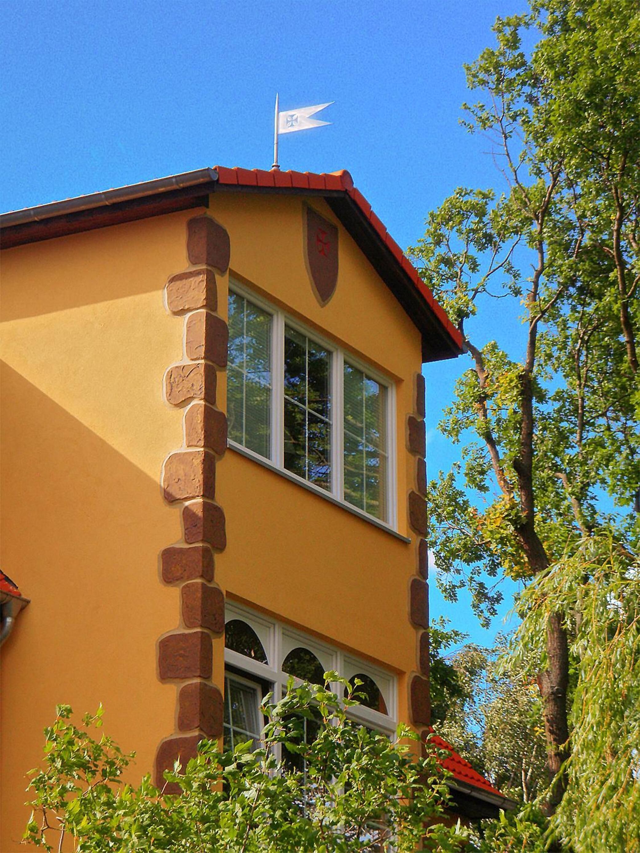 Ein gelbes Gebäude mit rotem Dach, steinernen Säulen und einer Flagge auf dem Dach.