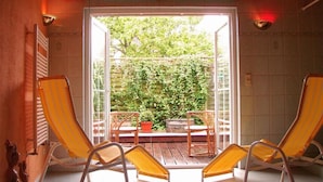 A room with two yellow-striped lounge chairs facing a sliding glass door leading to a balcony with a view of greenery. - Ostsee-Rittergut-Rügen – BinzHotel & OrdensKapelle (Binz)