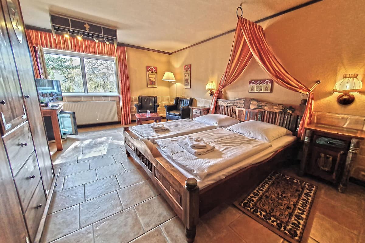 Een slaapkamer met een groot bed, een bureau met een computer en een stoel.