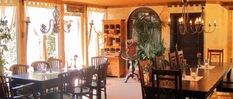 A dining area with wooden furniture, a chandelier, and a large window with curtains.