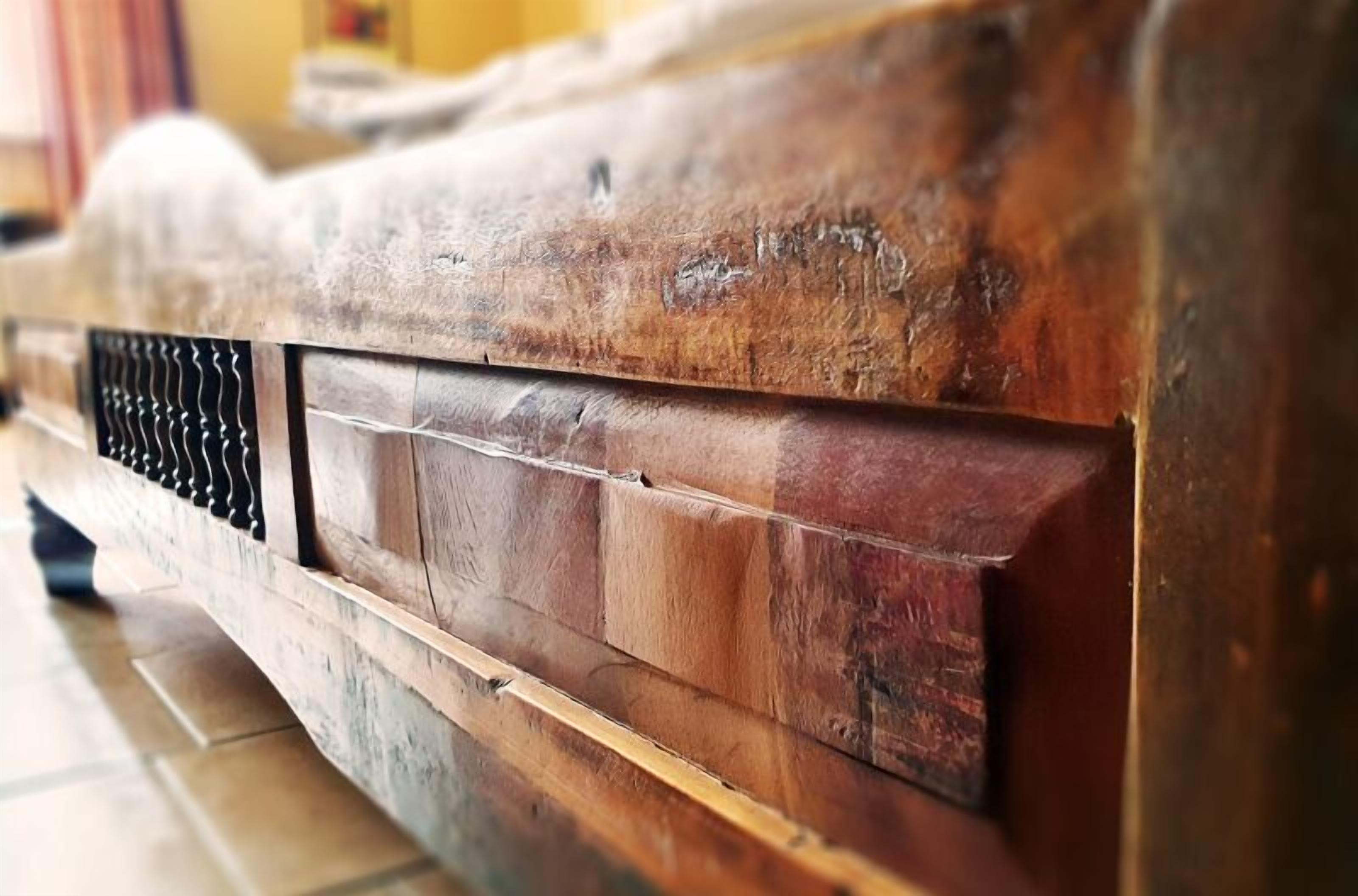 Detailaufnahme einer Holzkonstruktion mit strukturierter Oberfläche und einem Metallgitter.