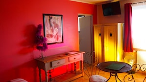 A room with a wooden console table, a framed artwork, a purple decorative plant, a small round table, and a wardrobe with a mirror. - Hôtel le Relais du Luberon (Maubec)