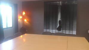 A conference room with a large table, chairs, a window with blinds, and a wall-mounted lamp. - Hôtel le Relais du Luberon (Maubec)
