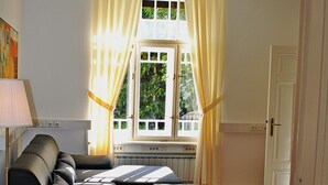 Een woonkamer met een bank, een houten salontafel en een raam met gordijnen.