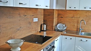 Een moderne keuken met houten aanrechtbladen, een inbouwfornuis en witte kasten.