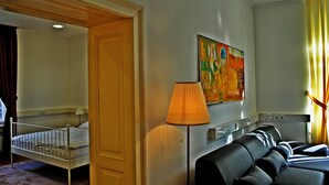 Een hotelkamer met een bed, een bank, een lamp en een schilderij aan de muur.