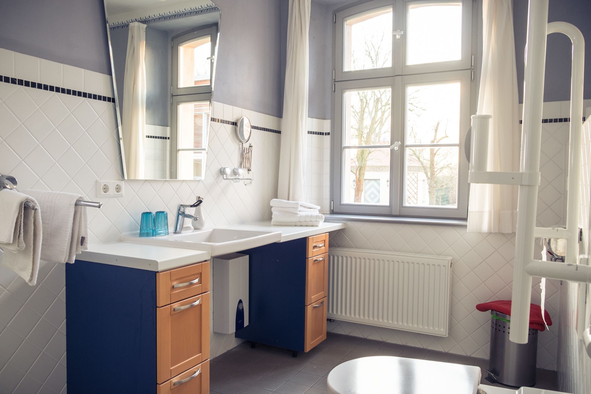 A modern bathroom with a double sink, a large mirror, and a window providing natural light.