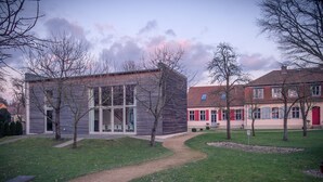 A modern building with a glass facade and a traditional red-roofed building nearby. - Grafschaft Kloster Zinna (Jueterbog)