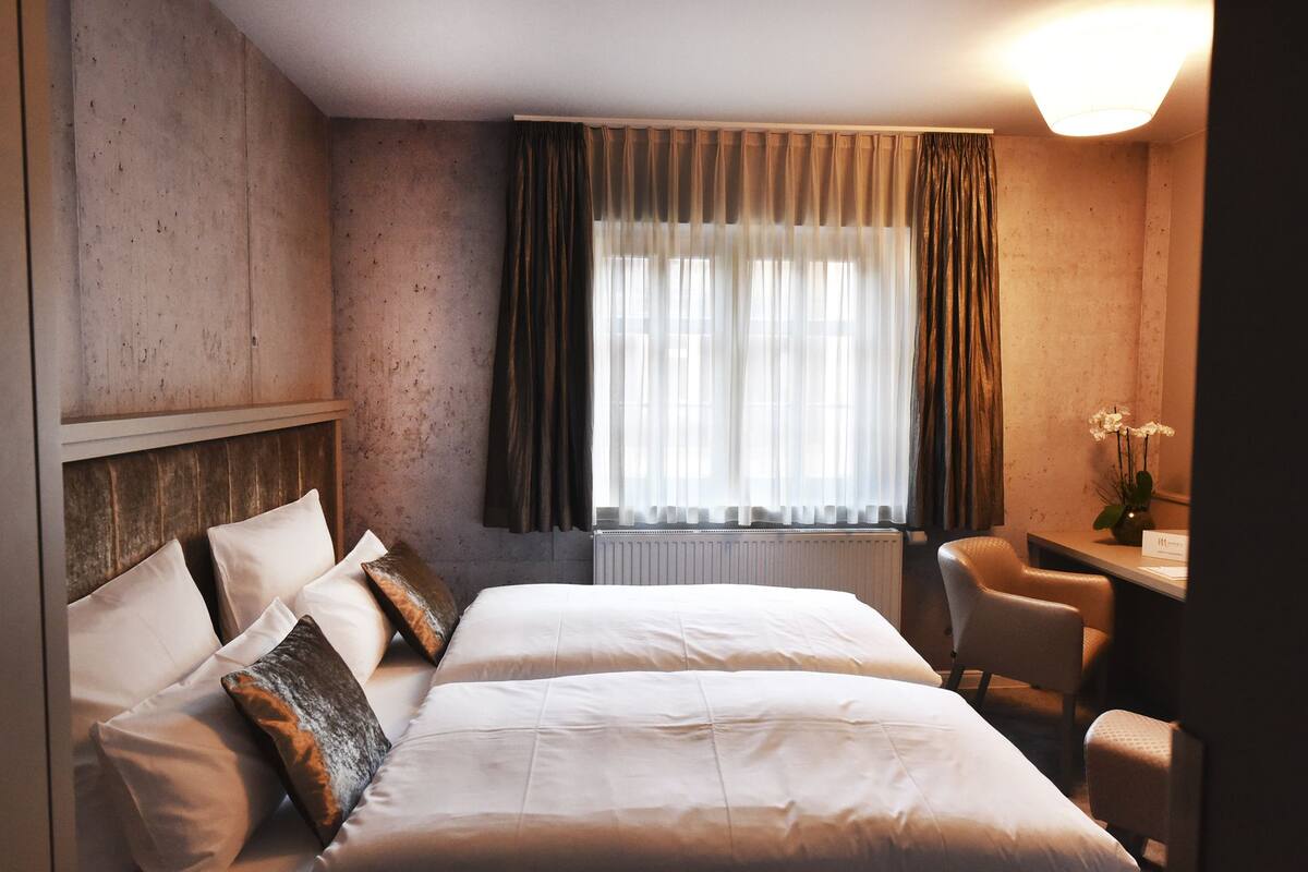A hotel room with a large bed, a desk, and a chair.