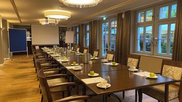 Ein Konferenzraum mit einem langen Tisch, Stühlen und einer Projektionsleinwand.