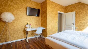 A hotel room with a bed, a desk with a chair, a television, and a door.