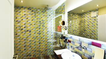 A bathroom with a tiled wall, a sink, and a mirror.