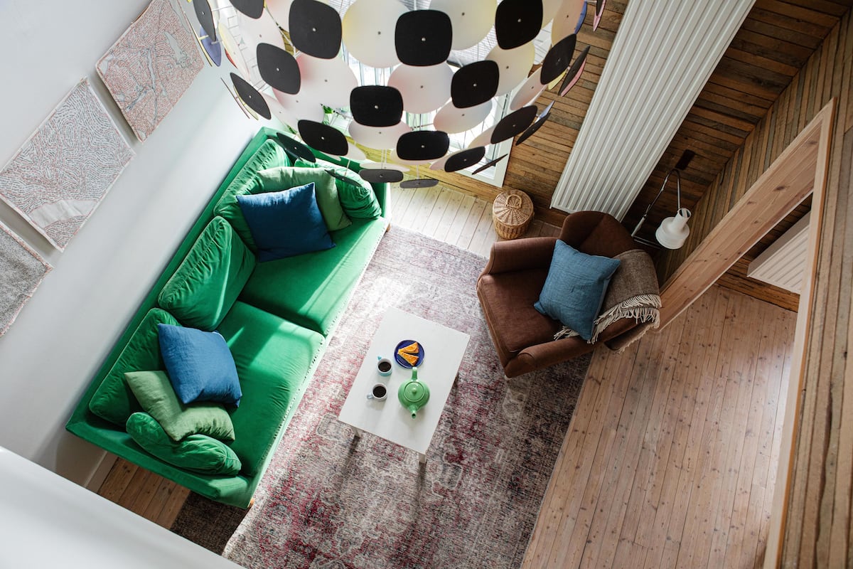 Uma sala de estar moderna com um sofá verde, uma poltrona marrom e uma mesa de centro branca com um bule e xícaras.