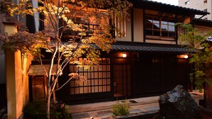 A traditional Japanese building with a wooden gate, a stone pathway, and a rock garden. - Village Kiramachi (Kyoto)
