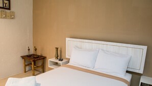 A hotel room with a large bed, a bedside table, a nightstand, and a wall-mounted shelf. - Hotel Avenija (Olongapo)